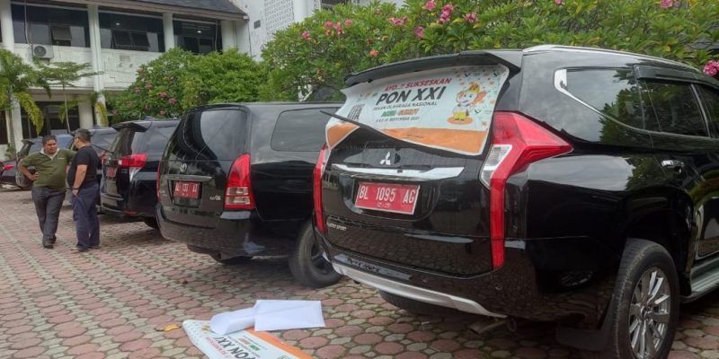 Proses penempelan stiker logo PON XXI pada mobil dinas Pemerintah Aceh di Halaman Parkir Kantor Gubernur Aceh, Banda Aceh, Jum'at, 24/5/2024). (foto: pemerintah aceh)